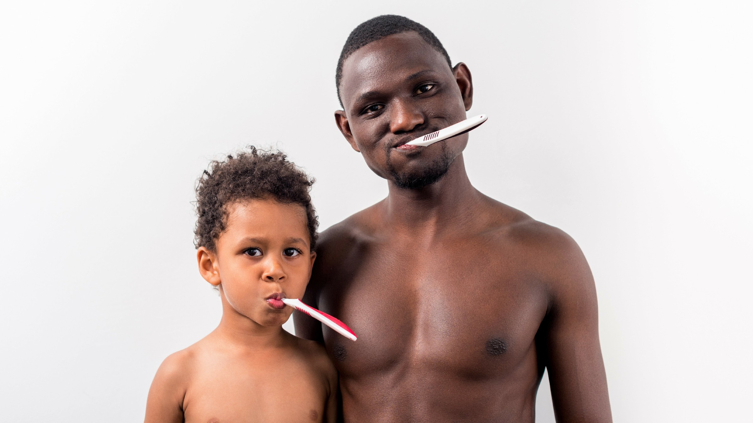A photo of a father with son brushing their teeth for oral health care