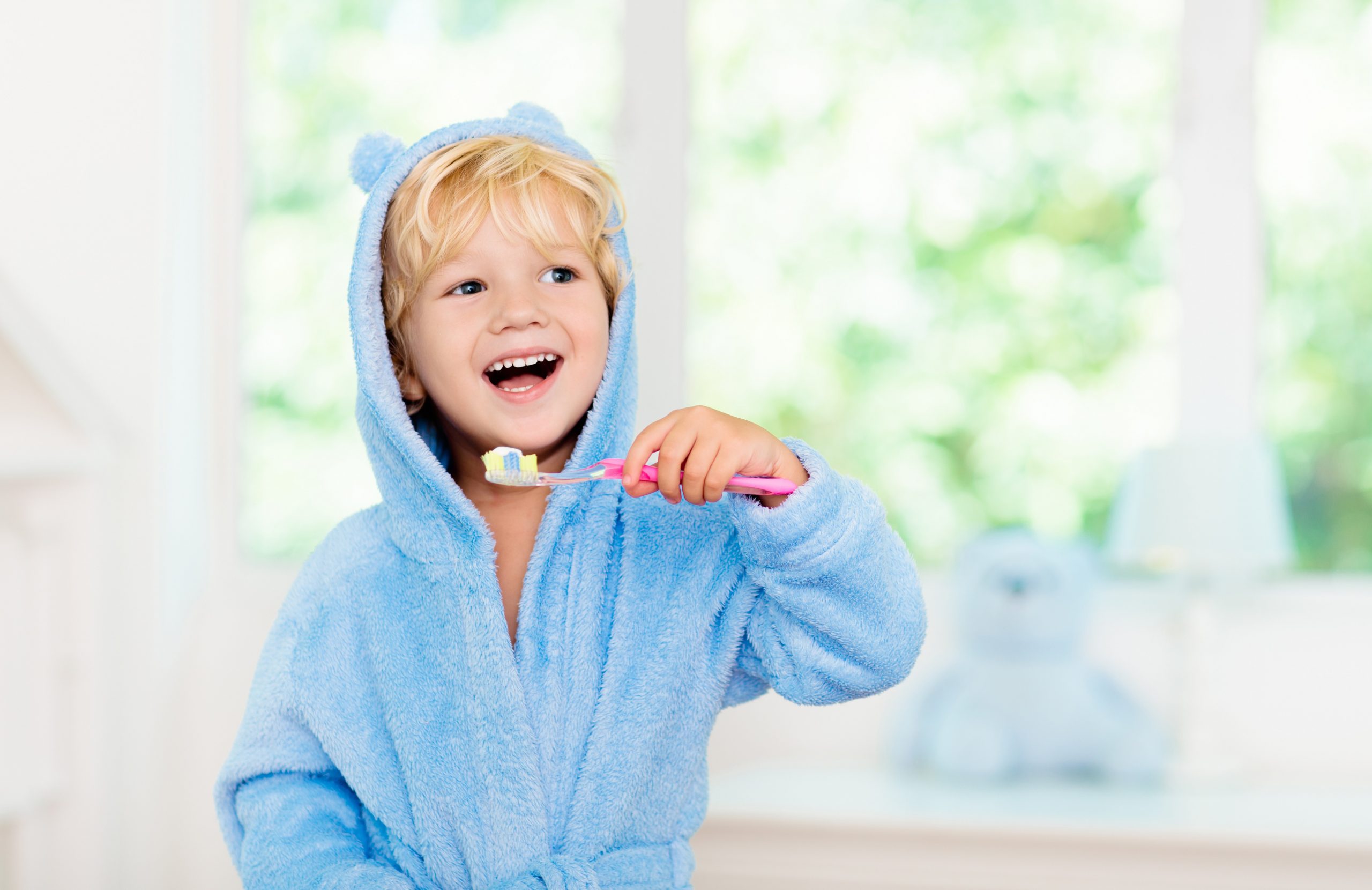 A happy young child holding a toothbrush